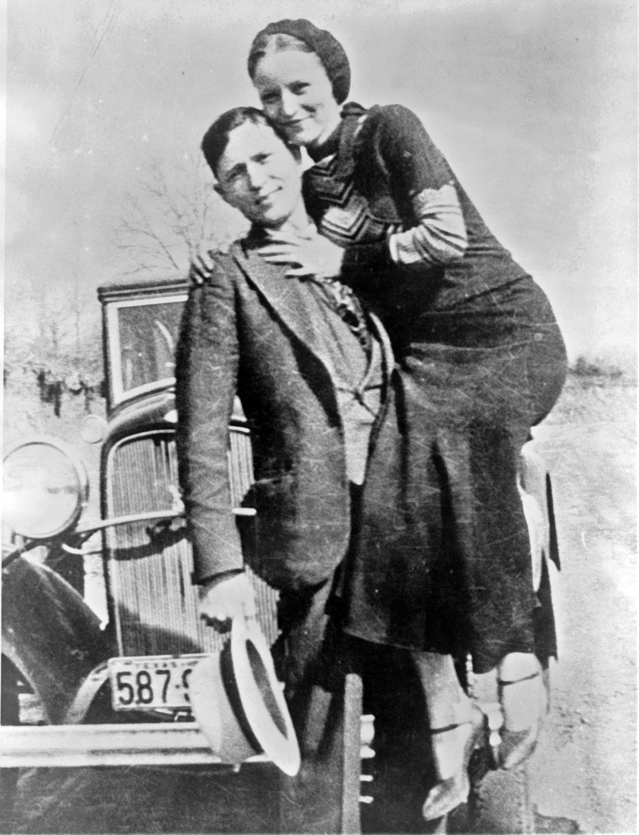 Bonnie Parker and Clyde Barrow, sometime between 1932 and 1934, when their exploits in Arkansas included murder, robbery, and kidnapping. Posing in front of a 1932 Ford V-8 automobile.jpg